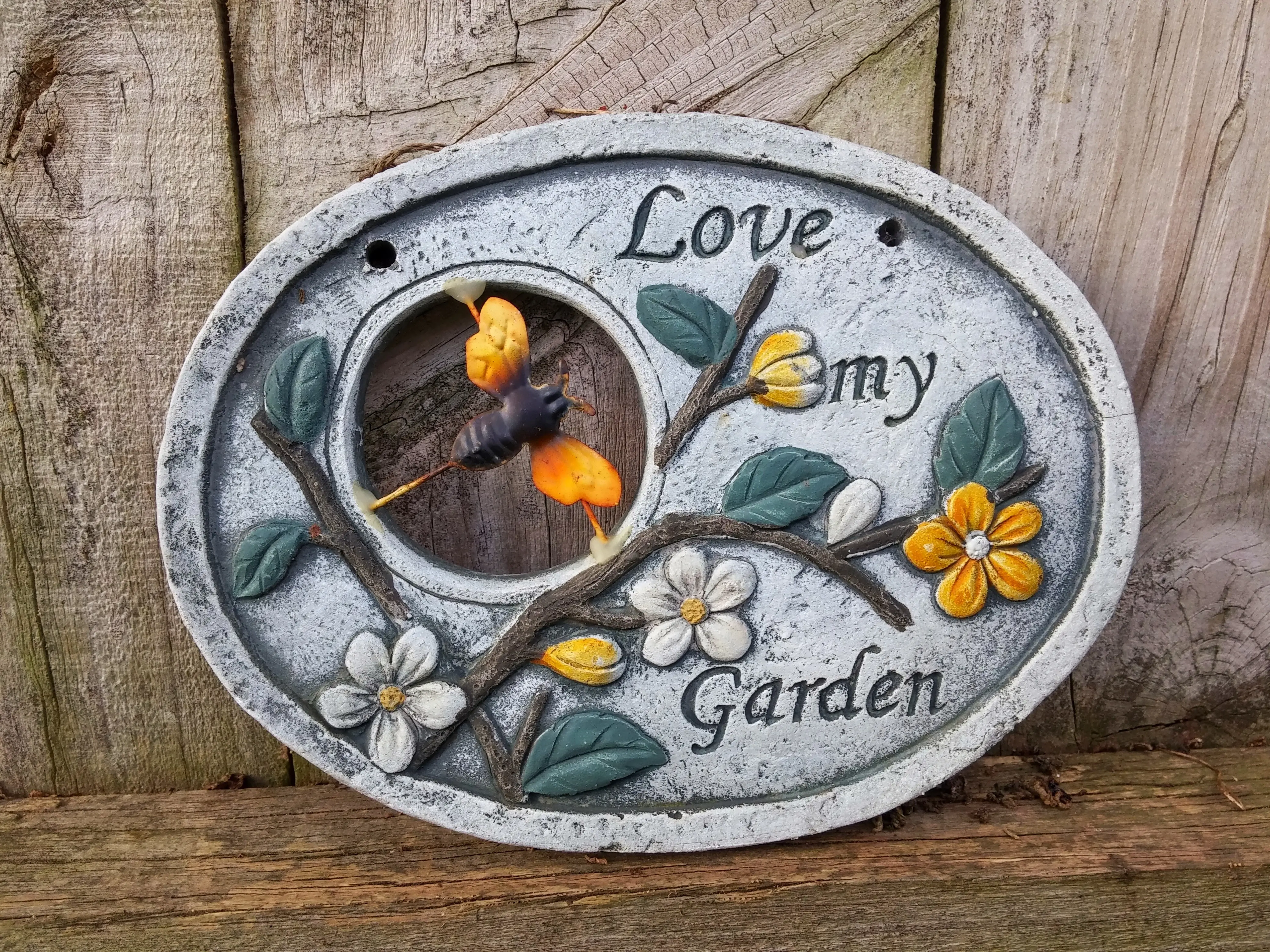 Nahaufnahme eines mehrfarbigen Kunstwerks vor einem Holzzaun.